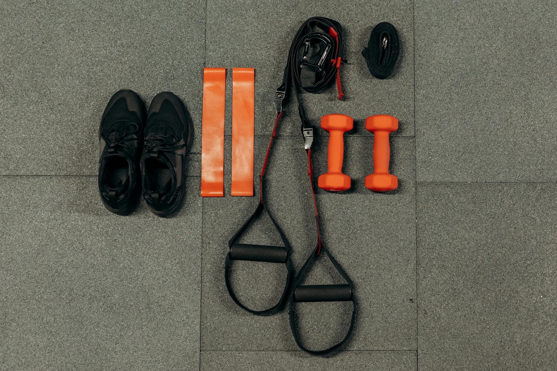 Overhead flatlay of training kit, dumbbells, sneakers, resistance bands, the weekly load of a Hyrox training protocol