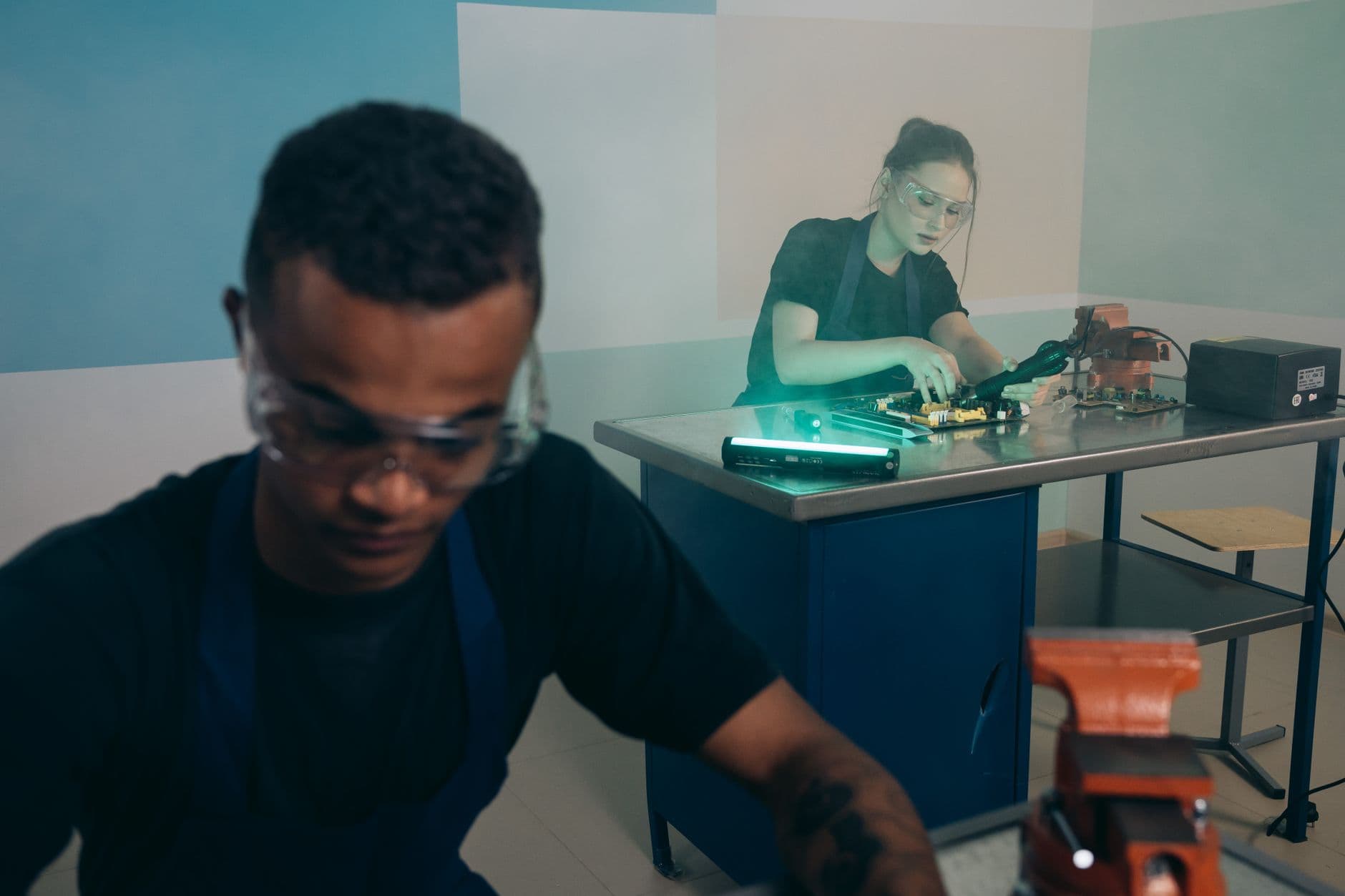 Two technicians working through a hardware problem at a lab bench, the hands-on model for training people to ship enterprise AI agents